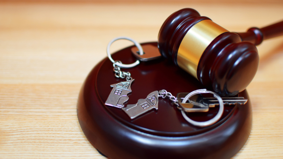 A gavel and a keychain on a wooden surface.