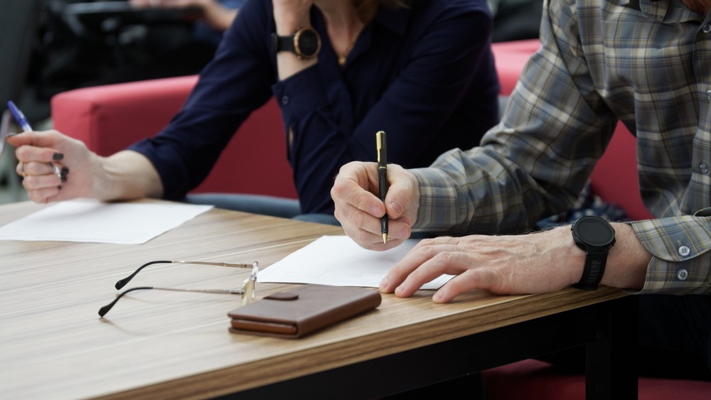 A man and woman writing on paper.